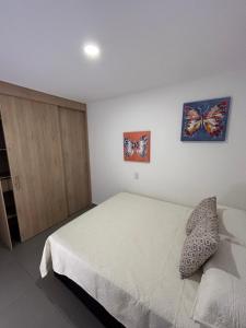 a bedroom with a bed and two butterflies on the wall at Apto cerca a la 10 del poblado in Medellín