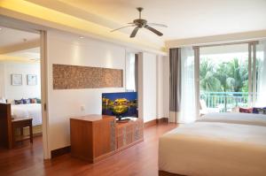 a bedroom with a bed and a flat screen tv at Huayu Resort & Spa Yalong Bay Sanya in Sanya