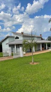 a white house with a palm tree in front of it at Casa com piscina em condomínio ensolarada! in Santa Bárbara do Rio Pardo +37 photos
