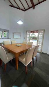 a dining room with a wooden table and white chairs at Casa com piscina em condomínio ensolarada! in Santa Bárbara do Rio Pardo