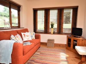 een woonkamer met een oranje bank en ramen bij 1 bed property in Banbury CC072 in Shotteswell