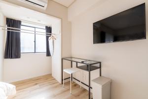 Kleines weißes Zimmer mit einem TV und einem Fenster. in der Unterkunft グランシャーギ in Osaka