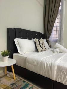 - un lit noir avec des oreillers blancs et une table dans l'établissement THREE ROOMS WITH WIFI HOMESTAY D’RAZAK IN KUALA TERENGGANU, à Kuala Terengganu
