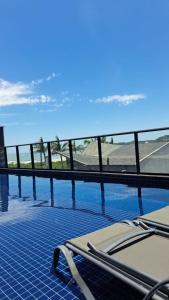 a swimming pool with two lounge chairs next to a fence at Apto Studio Square 990 - Vista Mar in Navegantes