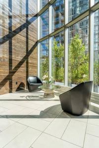 een lobby met 2 stoelen in een gebouw met ramen bij One Bed and Den Upscale Comfort Condo with Parking in Toronto