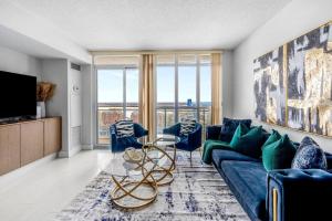 uma sala de estar com um sofá azul e uma mesa de vidro em One Bed and Den Upscale Comfort Condo with Parking em Toronto