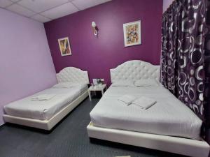 two beds in a room with a purple wall at Taman Negara River View Lodge in Kuala Tahan