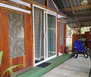 un porche de una casa con una silla y una ventana en Fully Furnished FAMILY JUNGLE TENT, Latino Glamping Paquera en Paquera