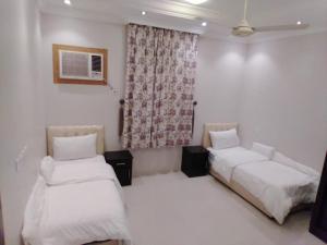 two beds in a room with white sheets and a window at سحاب فيو in Abha