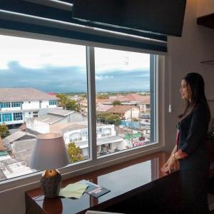 a woman standing in front of a large window at Sindoro Hotel Cilacap By Conary in Cilacap