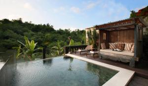 a swimming pool with a bench next to a house at Novus Giri Resort & Spa in Puncak