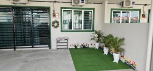 Habitación con alfombra verde y 2 ventanas en Teluk Intan Homestay Landed 3BR2B en Teluk Intan