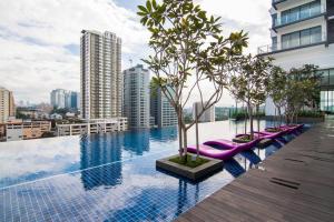 a swimming pool with purple lounge chairs on a building at Nadi Bangsar by Plush in Kuala Lumpur