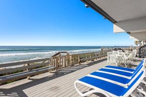 a deck with blue and white chairs and the ocean at Romantic Getaway - Luxury Oceanfront Studio - Private Balcony - Fireplace in Oceanside