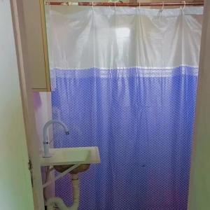 a bathroom with a blue shower curtain and a sink at Kitnet no Centro de São Pedro da Aldeia De frente para Lagoa in São Pedro da Aldeia
