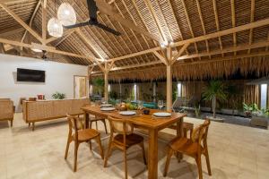 Villa Kelapa Kucing في غيلي آير: غرفة طعام مع طاولة وكراسي خشبية