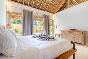 Villa Kelapa Kucing في غيلي آير: غرفة نوم بسرير ابيض ونافذة كبيرة