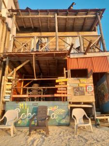 Mi Cabañita Guest House في بلايا بلانكا: مبنى على الشاطئ مع كرسيين
