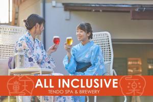 deux femmes assises dans des chaises tenant des verres de vin dans l'établissement Ichiraku tendo spa & brewery, à Tendō