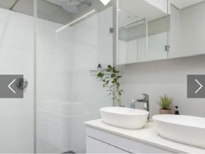 une salle de bain blanche avec deux lavabos et une douche dans l'établissement Franschhoek - La Petit Village - Views, à Franschhoek