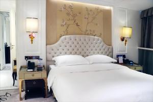 a bedroom with a large white bed with a large headboard at Estandon Hotel Guangzhou in Guangzhou