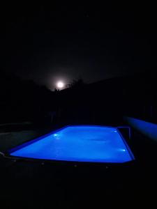 uma piscina azul à noite com a lua ao fundo em Casa de campo Maciel em Joanópolis