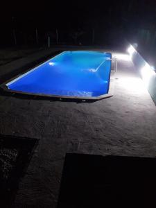 uma piscina azul à noite com luzes em Casa de campo Maciel em Joanópolis