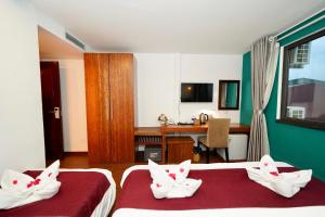 una camera da letto con due letti e una scrivania di NT Elysian hotel a Hanoi