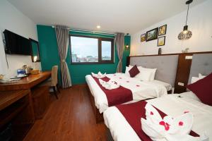 Habitación de hotel con 2 camas y escritorio en NT Elysian hotel en Hanoi
