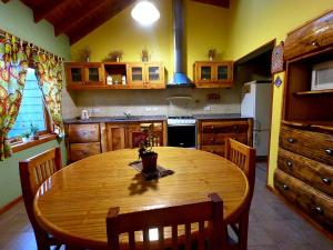 cocina con mesa de madera con sillas y nevera en Casas Nahuilen en San Martín de los Andes