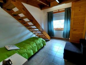 a bedroom with a green bed and a staircase at Casas Nahuilen in San Martín de los Andes