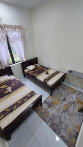 a bedroom with two beds and a window at Cinta Homestay Parit Raja UTHM in Parit Raja