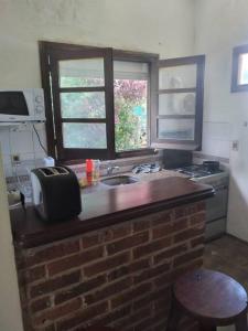 a kitchen with a brick counter with a sink and a window at Piriápolis a 4 cuadras de playa,"Las Hortensias" in Piriápolis