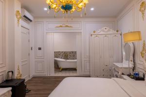 a bedroom with a tub and a bed and a chandelier at Pisces Hotel Hue in Hue
