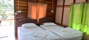 2 Betten in einem Zimmer mit grünen Vorhängen in der Unterkunft รายานี in Ko Por