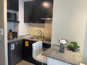 a kitchen with black cabinets and a counter with flowers on it at Atalaya Apartment Suite in Santiago