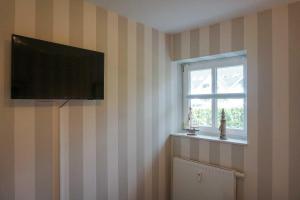 a room with a television on a striped wall with a window at DUeNENHOF-4 in Olsdorf