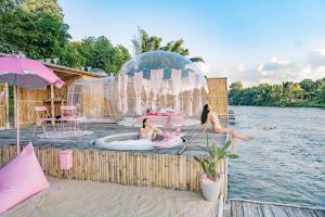 two girls are sitting in an igloo in the water at The Three Bubble Houses in Sai Yok