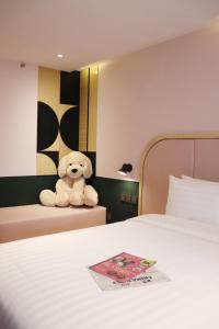 a stuffed teddy bear sitting on top of a bed at The Quarter Ratchathewi by UHG in Pom Prap
