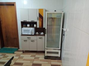 a small kitchen with a refrigerator and a microwave at Cantinho da Saudade in Campos do Jordão