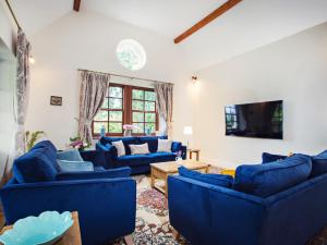 a living room with blue couches and a tv at 5 Bed in Bishops Frome 75602 in Bishops Frome