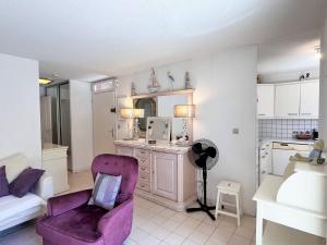 een woonkamer met een paarse stoel en een keuken bij Appartement Le Lavandou, 3 pièces, 4 personnes - FR-1-251-529 in Le Lavandou