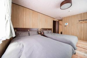 Habitación con 2 camas y paredes revestidas de madera. en Capricious INN kita27jyou en Sapporo