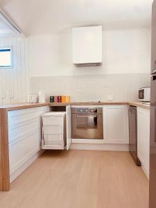 a white kitchen with white cabinets and appliances at Private Guest House in Wongawallan
