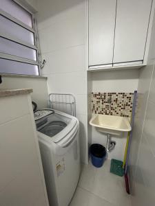 una pequeña cocina con lavadora y fregadero en Apartamento em Santos no Gonzaga em frente a praia en Santos