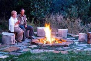 dos hombres sentados alrededor de un foso de fuego en un patio en Country Sunshine Bed and Breakfast en Durango