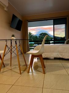 uma cadeira branca num quarto com uma cama e uma janela em Volcánico em La Fortuna