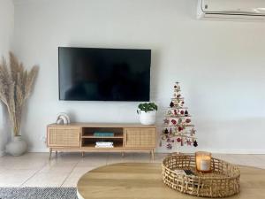 uma sala de estar com televisão e uma árvore de Natal em Cosy Beach House - Near Hot Springs. em Tootgarook