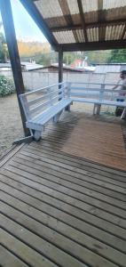 biała ławka siedząca na drewnianym pokładzie w obiekcie Casa en Niebla Valdivia w mieście Niebla