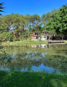 um lago com árvores e uma casa ao fundo em Chalé aconchegante em Itu